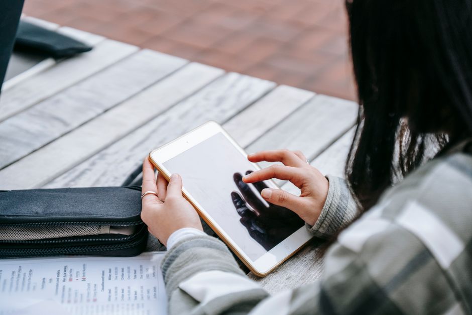 Pessoa utilizando um tablet ao ar livre, sugerindo tecnologia e comunicação digital.
