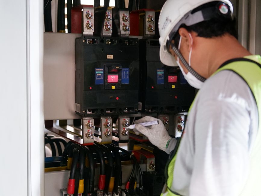 Técnico verificando e realizando manutenção em painel elétrico industrial para garantir segurança e funcionamento eficiente.