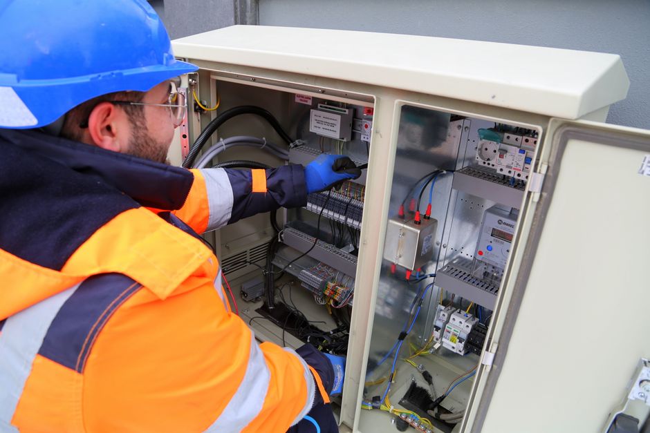 Técnico realizando manutenção em um quadro de Painel de Controle de sistemas elétricos ou automação industrial.