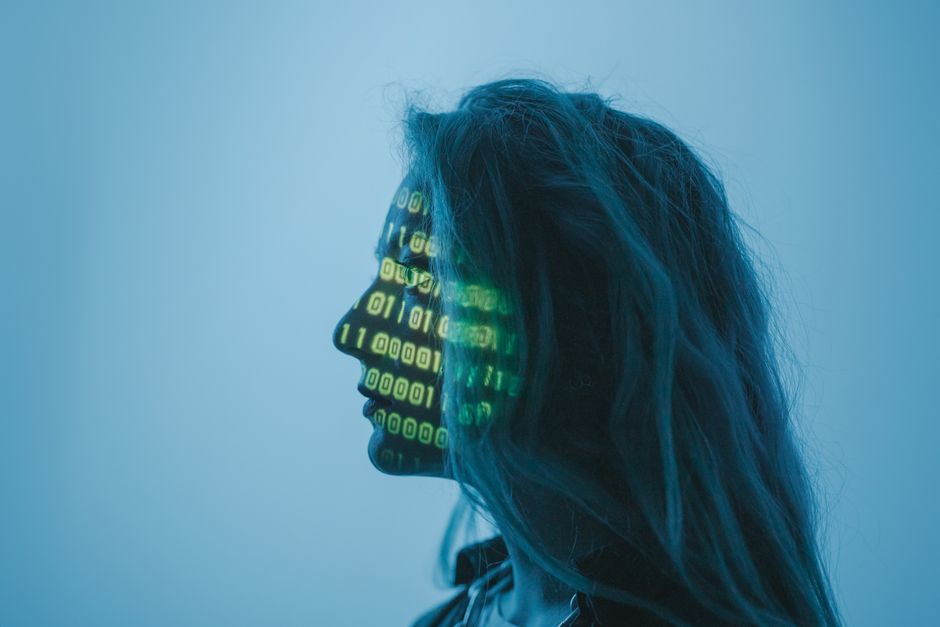Imagem conceitual representando a interação entre tecnologia e identidade humana, com uma silhueta de rosto humano projetada por códigos binários.