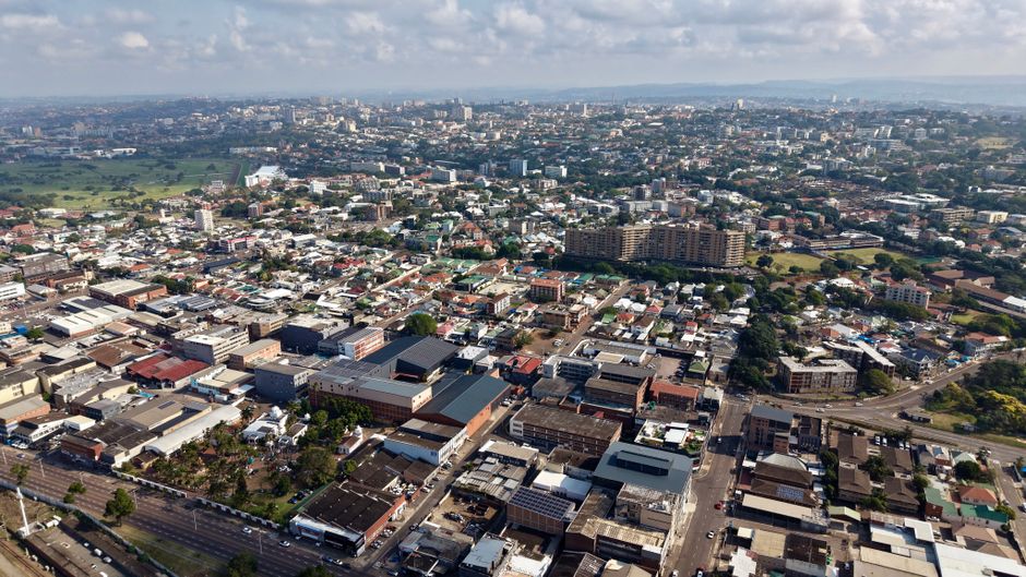 Vista aérea de uma cidade com uma mescla de áreas comerciais e residenciais, destacando o crescimento urbano e a infraestrutura urbana.