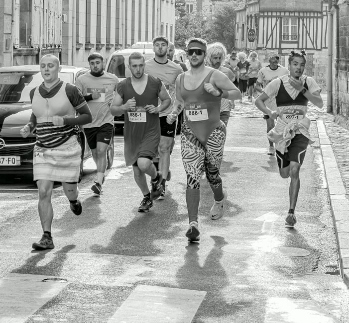 Grupo de corredores participando de uma corrida urbana em uma rua de cidade antiga.