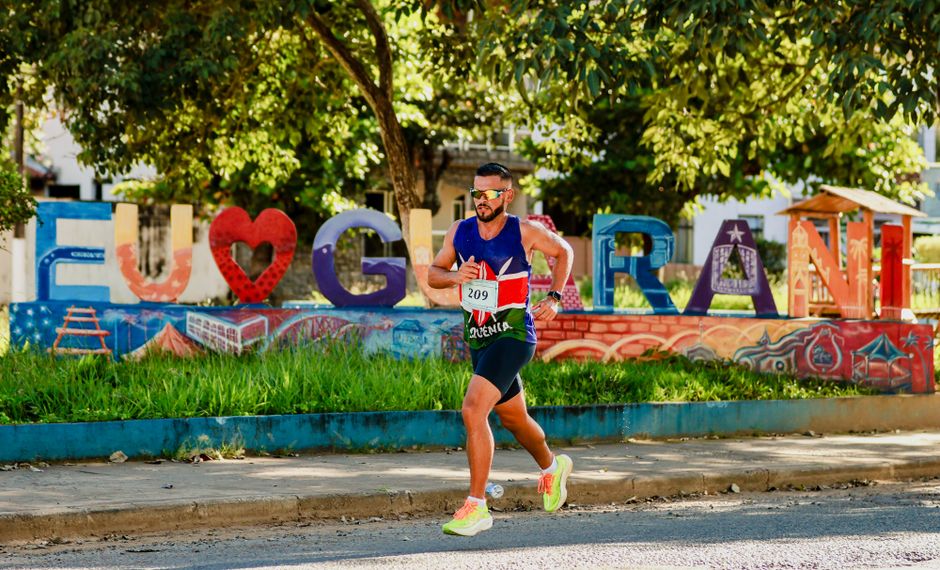 Corredor participando de uma corrida em uma rua decorada com palavras e símbolos de amor e cultura em Fuenlabrada, ao ar livre com árvores e grafite ao fundo.