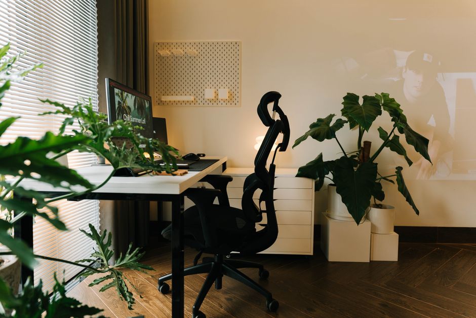 Imagem de um ambiente de trabalho moderno com mesa, cadeira ergonômica, computador, iluminação suave e plantas decorativas, ideal para artigos sobre home office e produtividade.