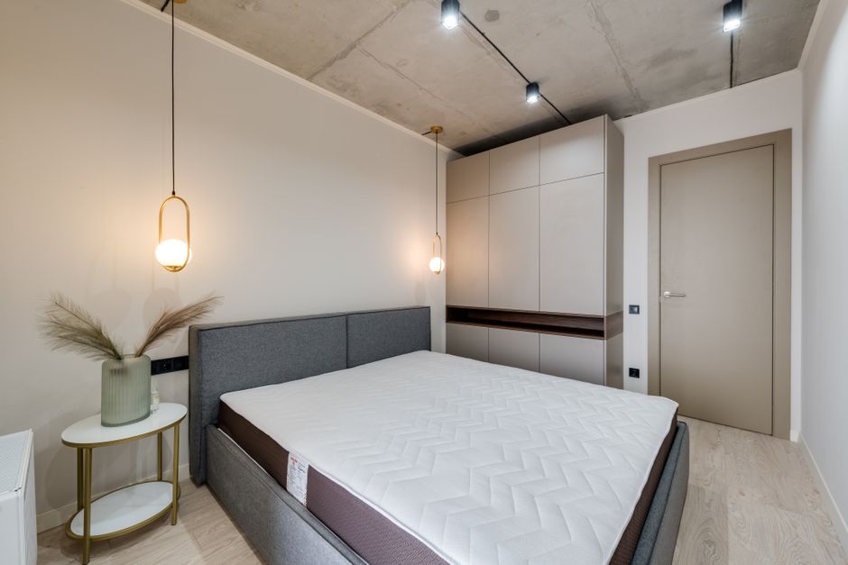 Quarto moderno com decoração clean, iluminação suave e mobiliário minimalista, ideal para apartamentos contemporâneos.