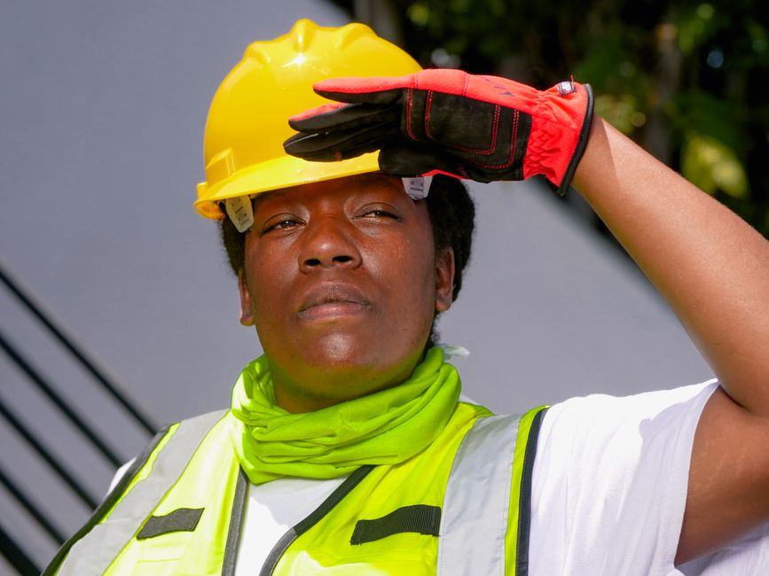 Profissional de segurança ou construção ajustando capacete ao ar livre, simbolizando atenção e responsabilidade no trabalho.
