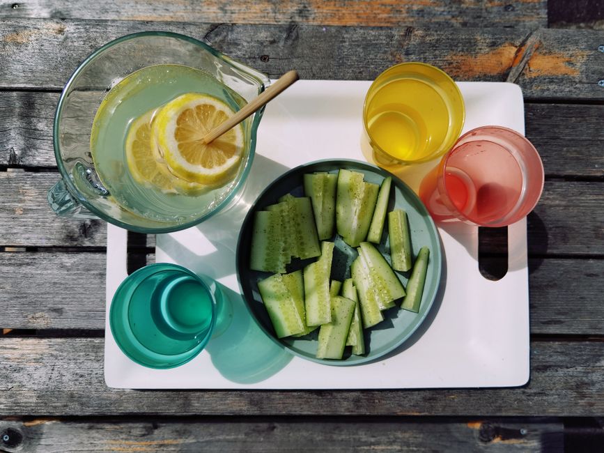 Imagem de uma limonada fresca acompanhada de pedaços de pepino, reforçando um tema de bem-estar e alimentação saudável ao ar livre.