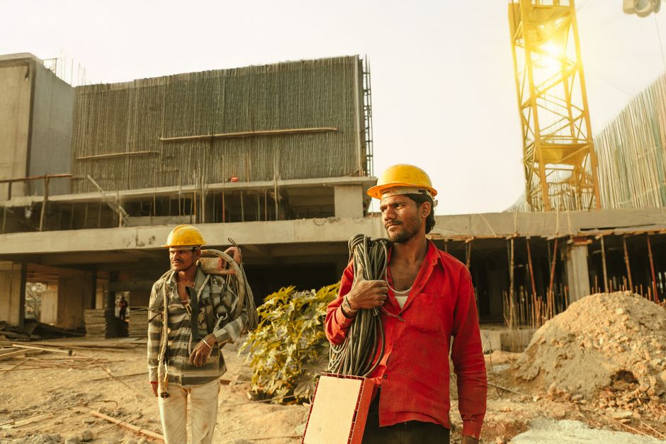 Engenheiros de construção em um canteiro de obras, discutindo planos de projeto com foco no desenvolvimento de uma estrutura arquitetônica.