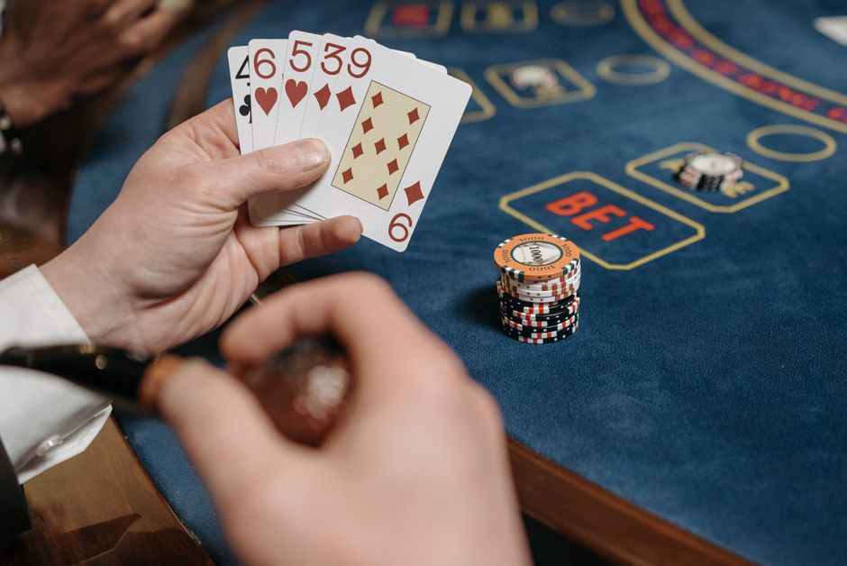 Imagem de uma mesa de cassino com foco em um jogo de pôquer, destacando as cartas, fichas de aposta e o ambiente de apostas.