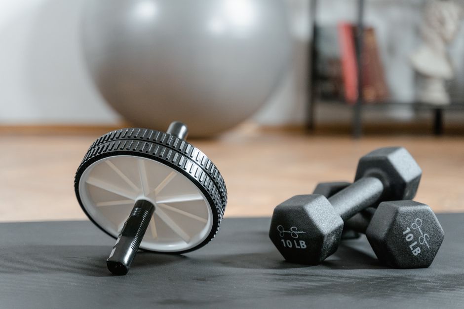 Imagem de equipamentos de fitness e exercícios físicos com pesos e um dispositivo de rotação, ideal para conteúdos sobre treino e saúde.