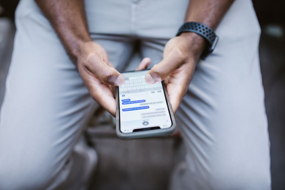 Pessoa utilizando smartphone para comunicação, representando conexões pessoais ou profissionais em um ambiente informal.