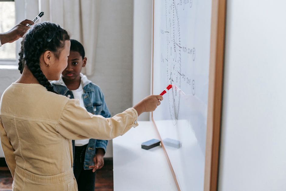 Professor ensinando uma criança a resolver equações matemáticas na sala de aula.