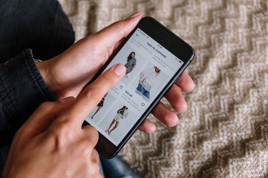 Pessoa pesquisando compras de roupas online, evidenciando o uso de tecnologia no comércio varejista.
