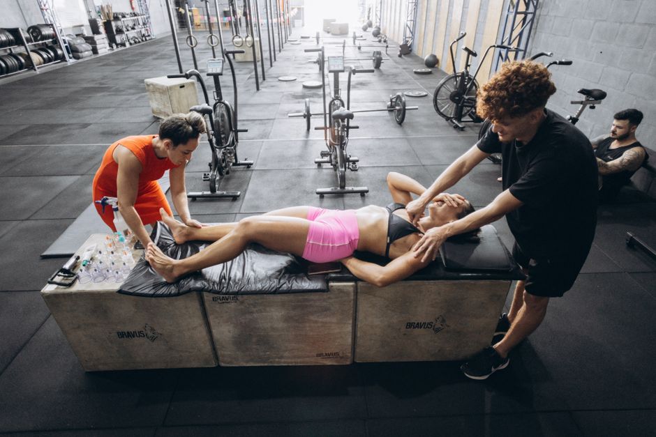 Mulher recebendo atendimento de um fisioterapeuta durante exercícios de recuperação em uma academia de crossfit.