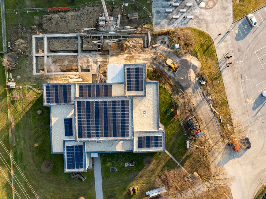 Vista aérea de uma construção residencial com painéis solares no telhado, destacando o tema de sustentabilidade e energia renovável em projetos de habitação urbana.