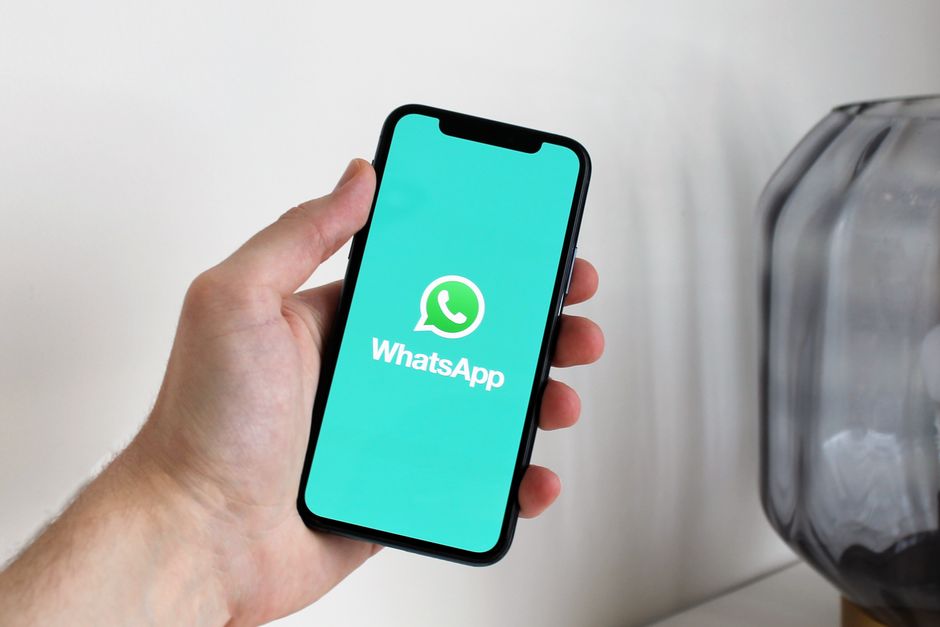 Pessoa segurando um smartphone exibindo o aplicativo WhatsApp, com foco na comunicação digital moderna.