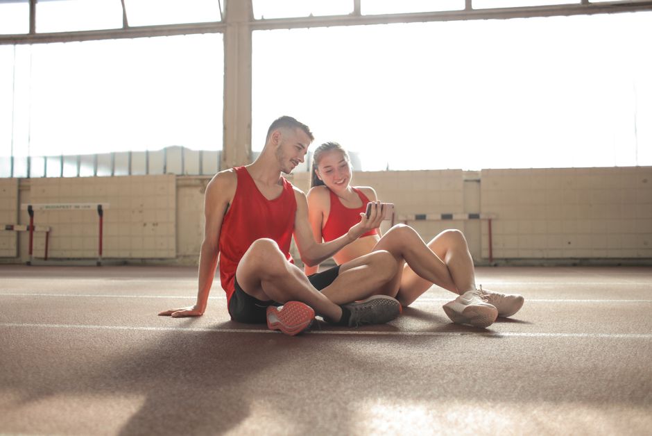Juventude relaxando após atividade física em ambiente esportivo, usando roupas esportivas e aproveitando o momento juntos.