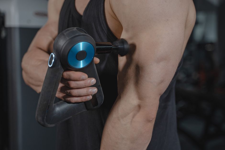 Pessoa realizando treino de musculação, focando no exercício de braço com equipamento de resistência, em um ambiente de academia.