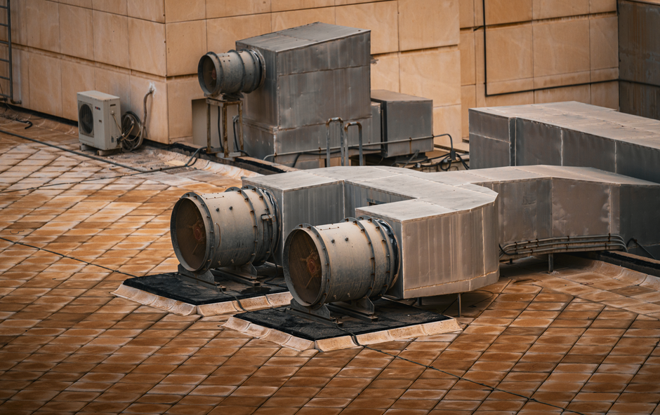 Imagem de sistemas de ventilação no telhado de um edifício, evidenciando infraestrutura de climatização ou ventilação industrial.