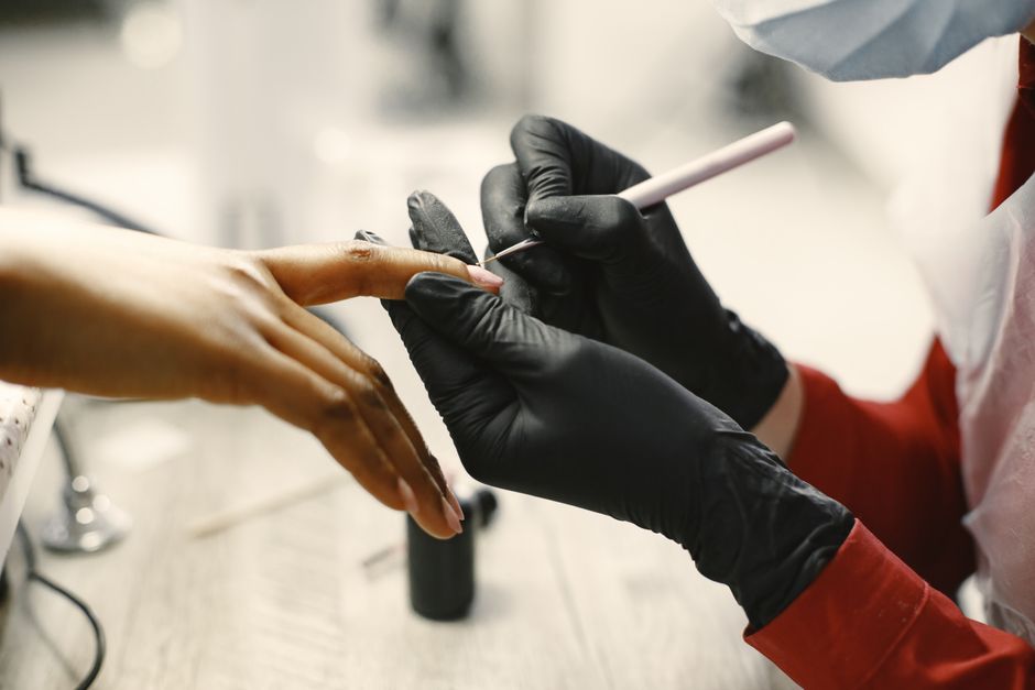 Profissional realizando uma manicure em uma cliente, destacando os cuidados com a estética e saúde das unhas.