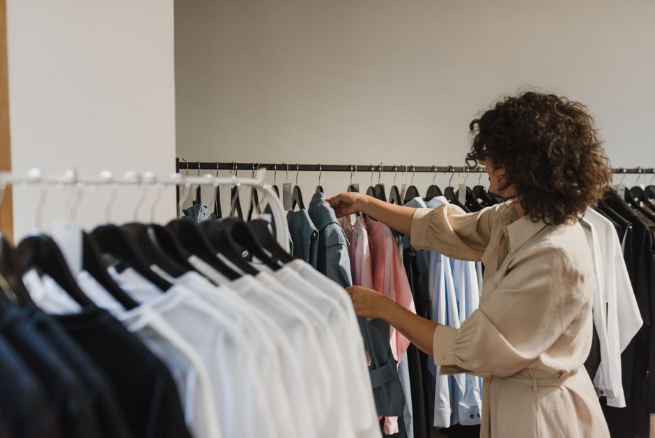 Mulher analisando roupas em uma loja de vestuário, ilustrando o tema de consumo, moda ou comércio de roupas.
