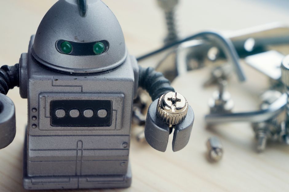 Robô de brinquedo com peças de montagem ao fundo, simbolizando tecnologia e inovação.