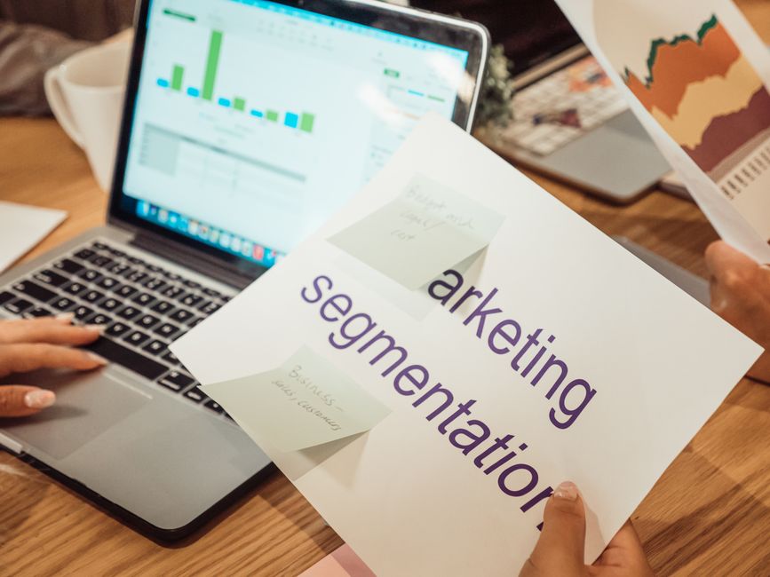 Pessoa apresentando uma estratégia de marketing para segmento de negócios, com gráficos de desempenho na tela do notebook.