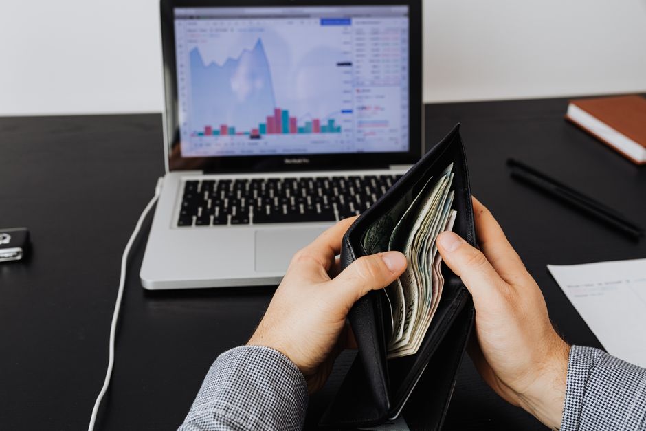 Pessoa verificando finanças pessoais com planilhas e gráficos digitais em ambiente de trabalho.