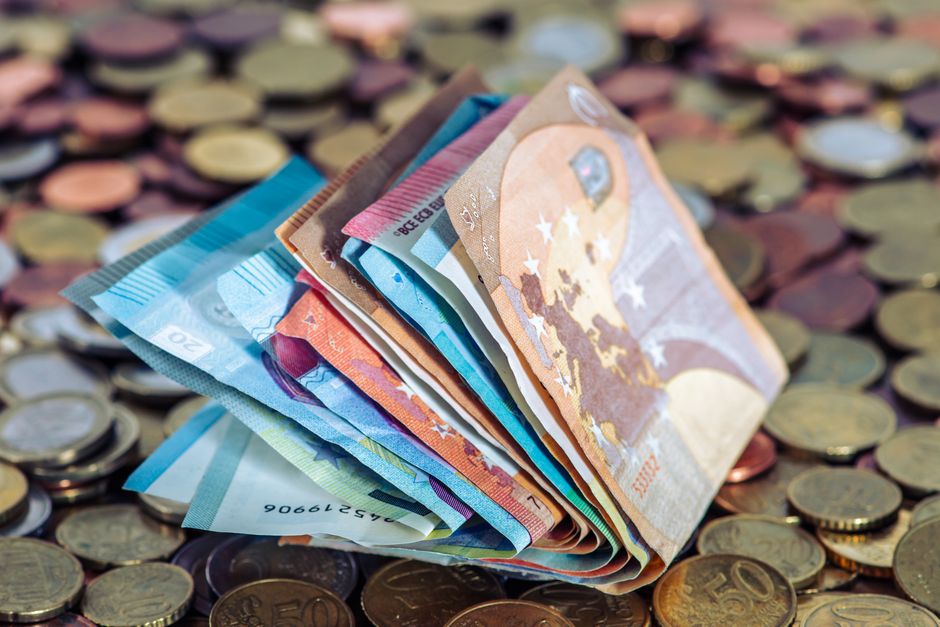 Imagem de dinheiro em euros em cima de moedas, simbolizando economia ou gestão financeira.