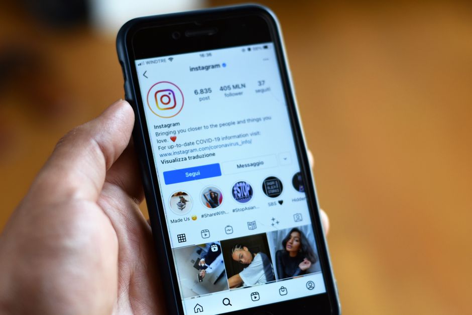 Pessoa segurando um smartphone exibindo o perfil do Instagram, destacando o uso de redes sociais na comunicação digital.