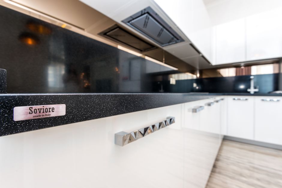 Imagem de uma cozinha moderna com bancada de granito preto e armários brancos, ideal para ilustrar design de interiores ou tendências em cozinhas contemporâneas.