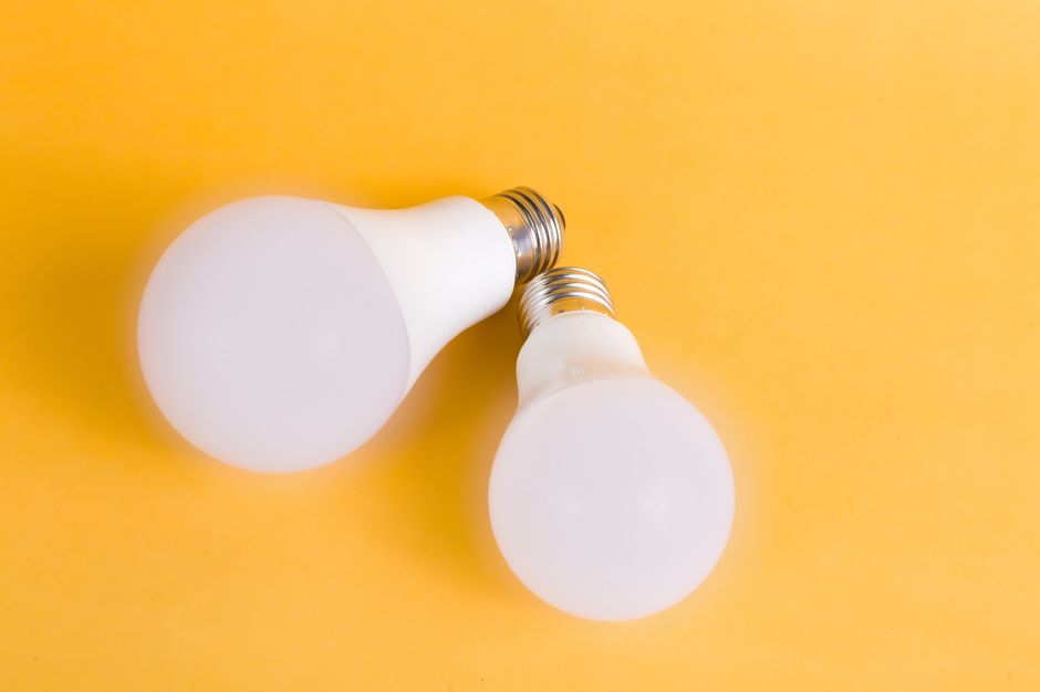 Imagem de duas lâmpadas de LED brancas sobre fundo amarelo, simbolizando inovação e economia de energia.