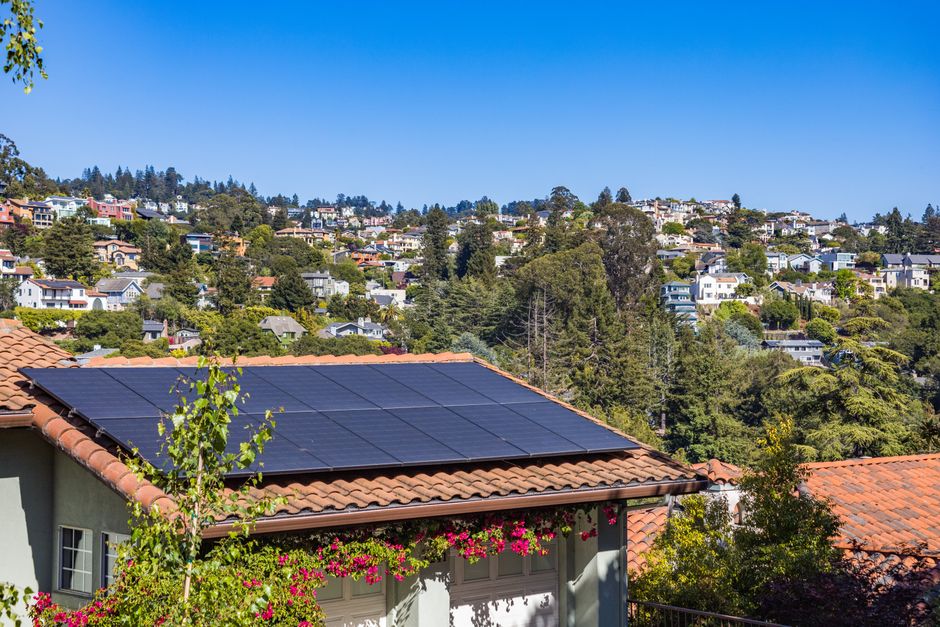 Paisagem de uma área residencial com painéis solares instalados em telhado, destacando sustentabilidade e energia renovável na cidade.