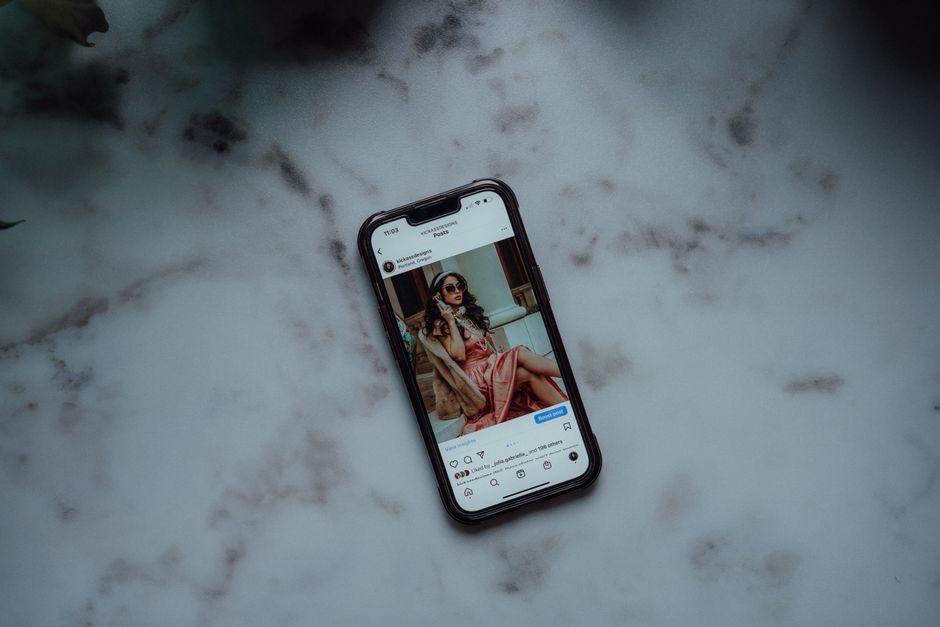 Foto de um smartphone exibindo uma postagem de mulher estilosa usando óculos escuros, enfatizando o tema de mídias sociais e lifestyle.