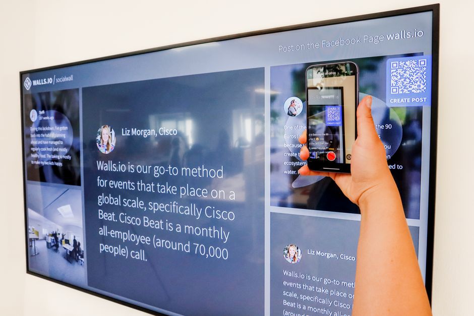 Pessoa gravando a tela de um painel digital com celular, em um ambiente de escritório, destacando comunicação e tecnologia no ambiente de trabalho.