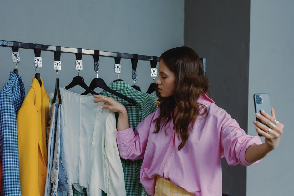 Mulher fazendo store check e avaliando roupas em um provador ou loja de moda, refletindo tendências de consumo e estilo de vida.