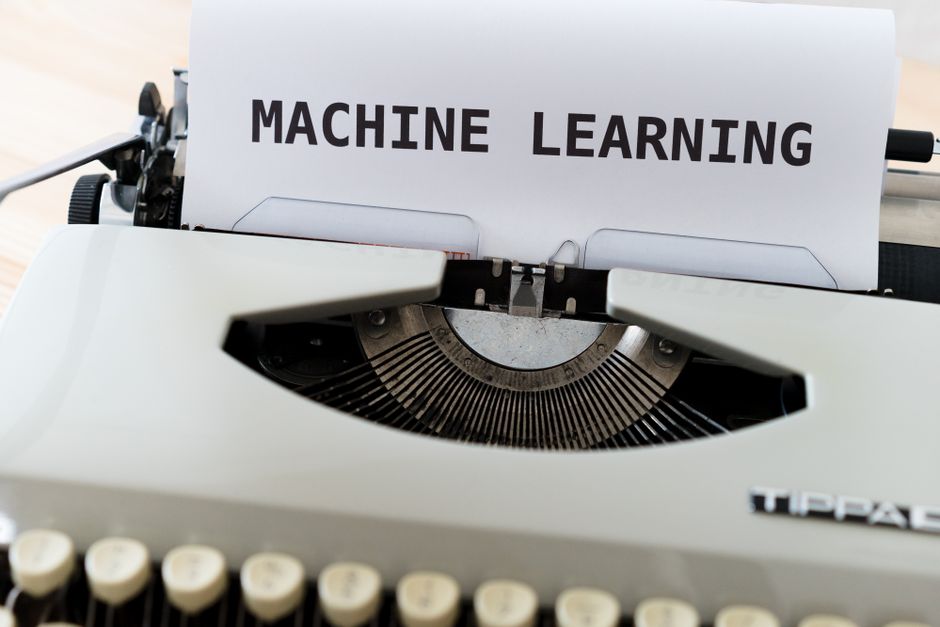 Imagem de uma máquina de escrever com uma folha de papel contendo o texto 'Machine Learning', simbolizando o tema de inteligência artificial e tecnologia.