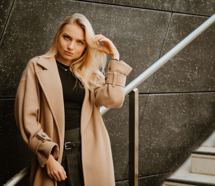 Mulher elegante posando casualmente ao lado de uma escada, transmitindo estilo e autoconfiança para artigos sobre moda e lifestyle.