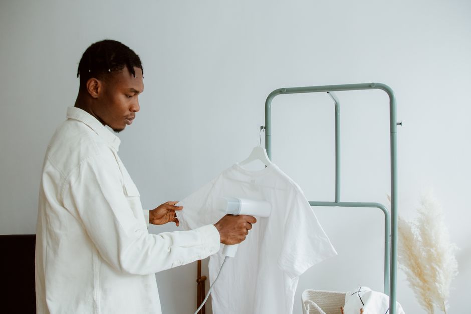 Pessoa utilizando um secador de roupa em uma camisa branca, simbolizando cuidado com tecidos ou métodos de limpeza.