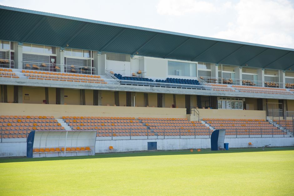 Imagem de um estádio de futebol vazio, destacando os assentos e o campo bem cuidado, ideal para ilustrar temas relacionados a esportes, eventos esportivos ou gestão esportiva.
