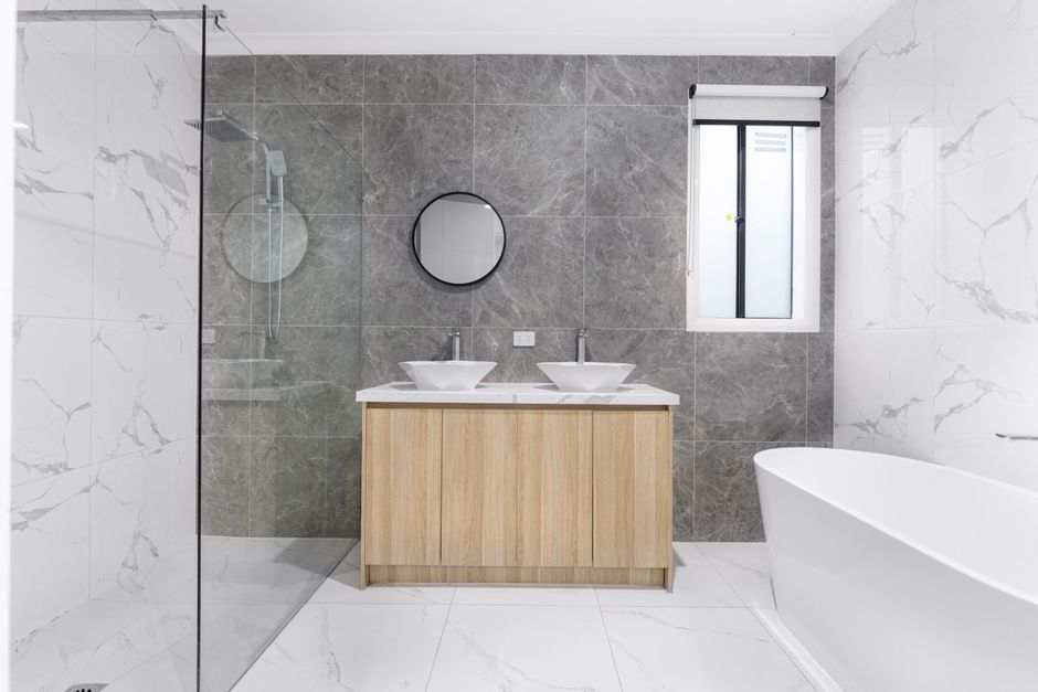 Banheiro moderno com banheira, espelho e pia dupla, trazendo um ambiente clean e elegante.