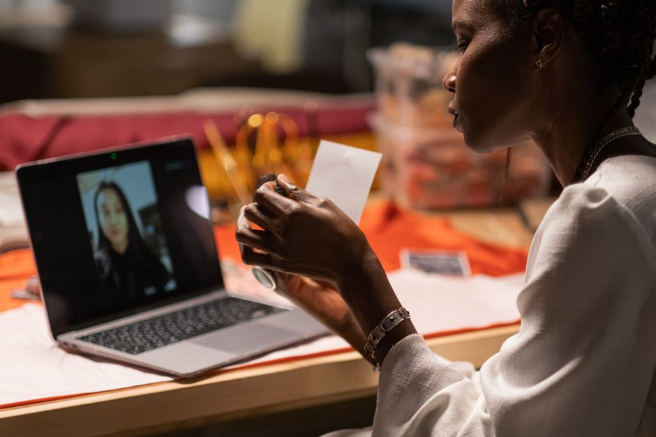 Mulher participando de uma reunião virtual, concentrada em sua troca de informações diante de um notebook em um ambiente de trabalho doméstico ou escritório.