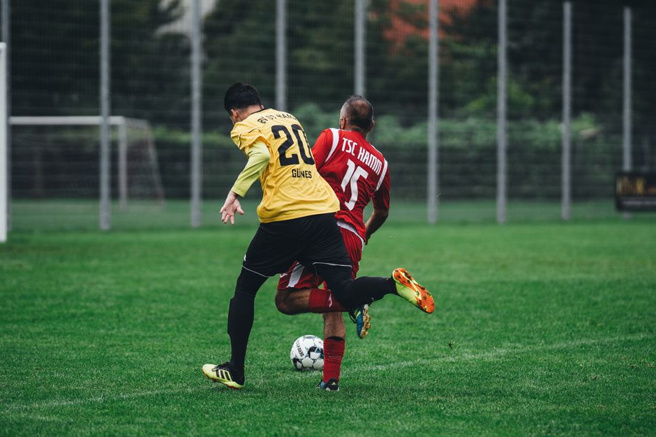 Dois jogadores de futebol em ação durante uma partida no campo, disputando a posse da bola.