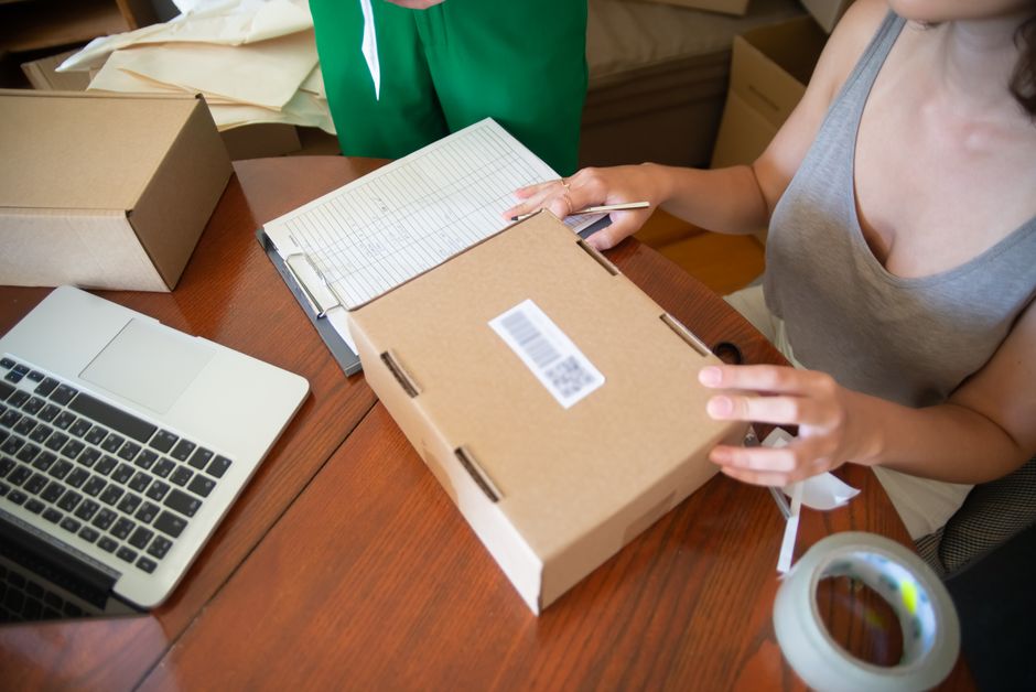 Imagem de uma mulher lidando com embalagem de produtos para comércio eletrônico, simbolizando o processo de envio e logística de negócios online.