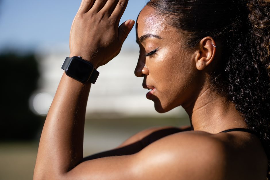Mulher tentando aliviar o calor após prática de exercícios ao ar livre, destacando rotina de saúde e bem-estar.