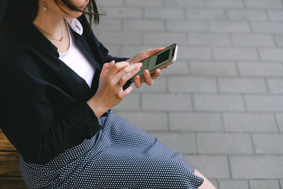 Mulher utilizando o smartphone em ambiente urbano, representando conectividade e uso de tecnologia no cotidiano.
