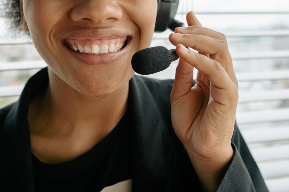 Pessoa sorridente usando headset de atendimento ao cliente em ambiente de trabalho profissional.