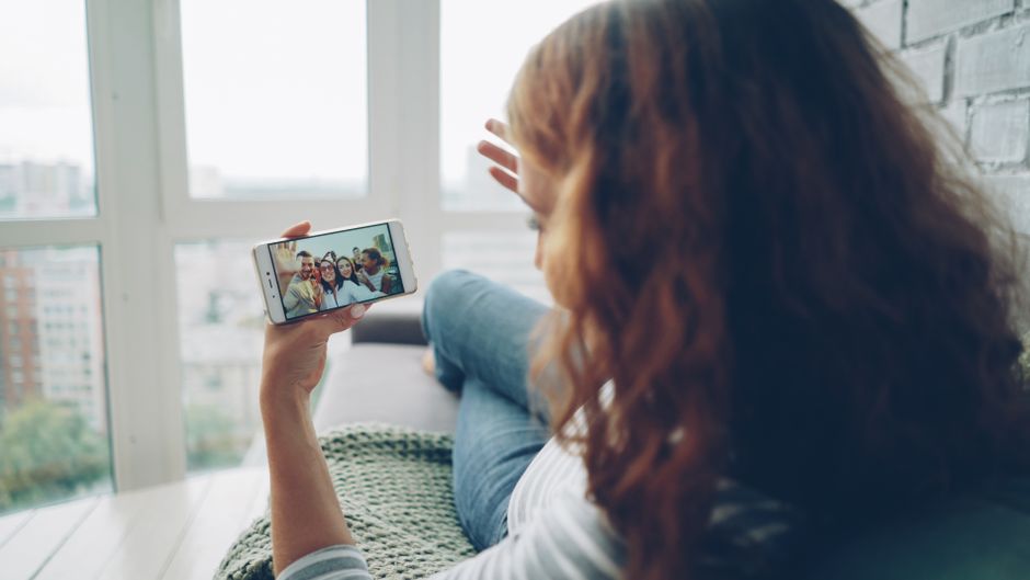 Mulher relaxando em casa enquanto participa de uma videochamada pelo celular, transmitindo conexão e comunicação digital.