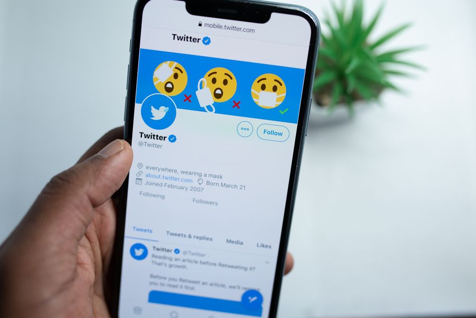 Imagem de um smartphone exibindo a página inicial do Twitter com emojis de reações, ilustrando o uso de redes sociais para comunicação e expressão digital.