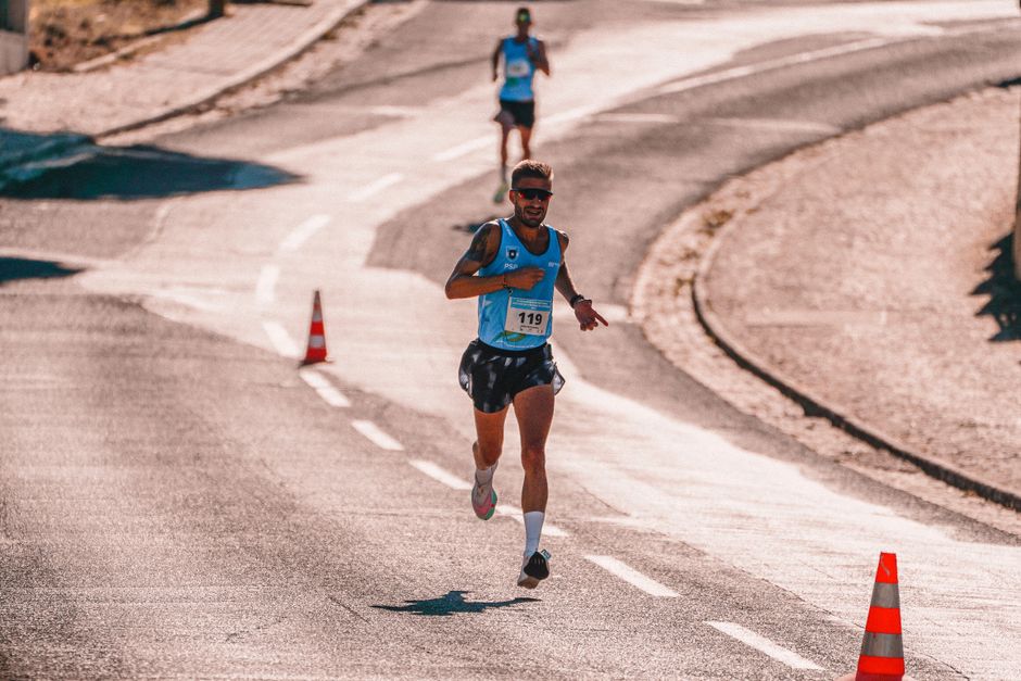 Atleta participando de uma corrida de rua ao longo de uma estrada sinuosa em clima de competição e resistência.
